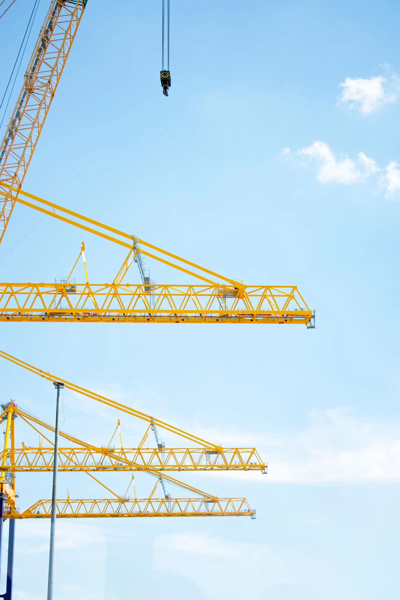 Tower crane booms against a blue sky